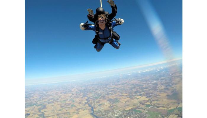 Austin Elmer poses for a photo mid-air while tandem skydiving