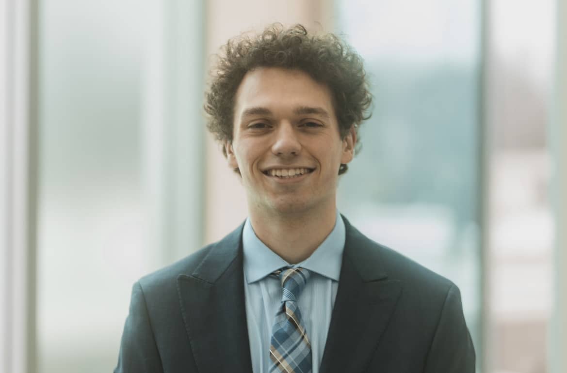 Austin poses for a professional headshot in a suit and tie