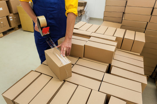 employee manually packaging cardboard boxes in warehouse